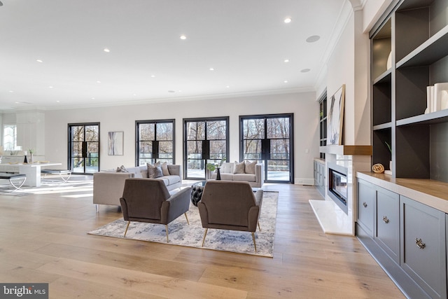 living room featuring light wood finished floors, a high end fireplace, baseboards, ornamental molding, and recessed lighting