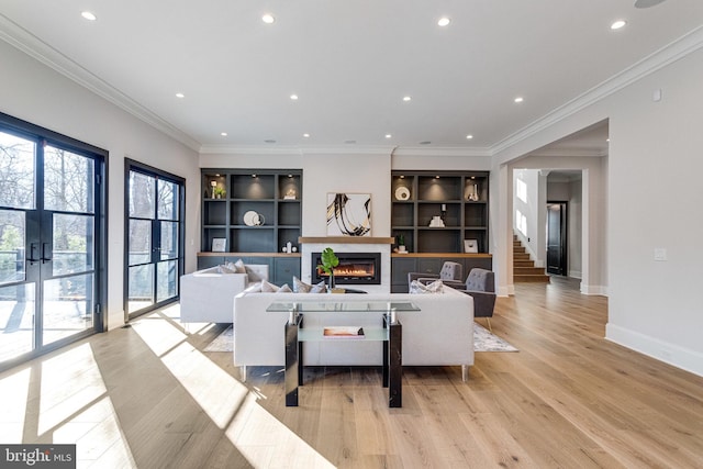 living room featuring built in shelves, baseboards, recessed lighting, a glass covered fireplace, and light wood-type flooring