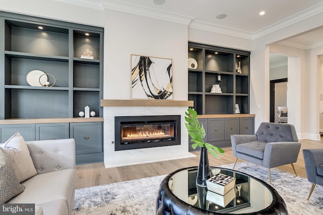 living room with built in shelves, ornamental molding, a premium fireplace, recessed lighting, and wood finished floors