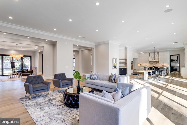 living room featuring recessed lighting, a notable chandelier, light wood-style floors, and crown molding