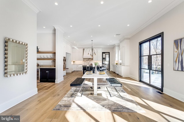 dining room featuring beverage cooler, baseboards, light wood-style floors, and ornamental molding