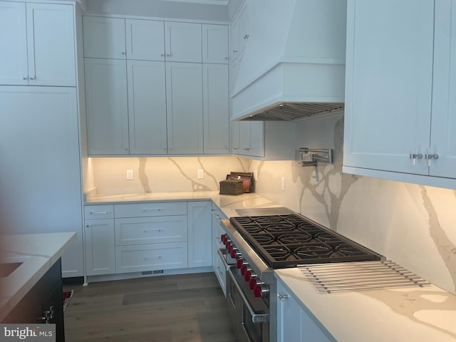 kitchen with range with two ovens, custom exhaust hood, wood finished floors, and light countertops