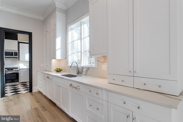 kitchen with crown molding, white cabinets, appliances with stainless steel finishes, and a sink