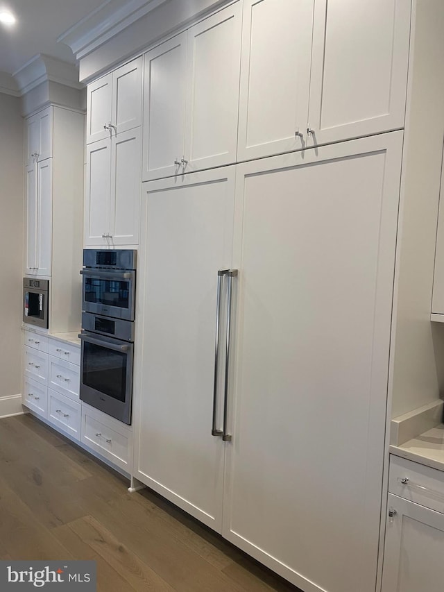 kitchen with stainless steel double oven, light countertops, and white cabinetry