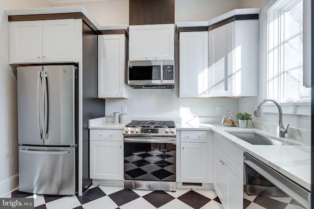 kitchen featuring a sink, white cabinets, light floors, and stainless steel appliances