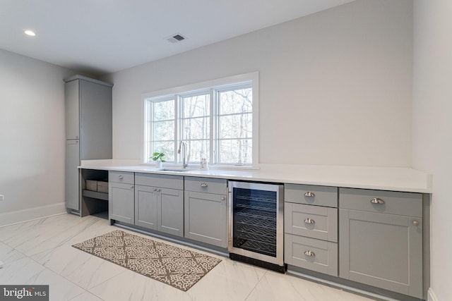 bar with baseboards, visible vents, a sink, wine cooler, and marble finish floor