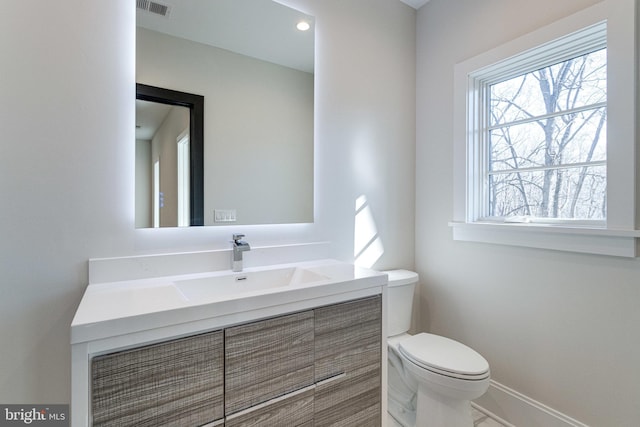 bathroom with vanity, toilet, baseboards, and visible vents