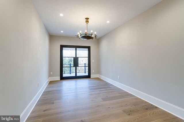 empty room featuring baseboards, a chandelier, recessed lighting, french doors, and light wood-style floors