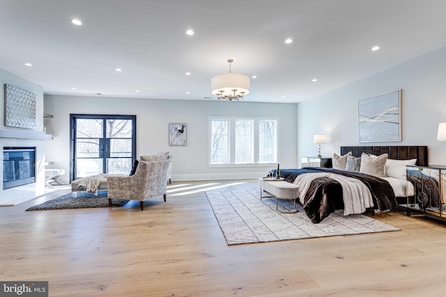 bedroom with a glass covered fireplace, recessed lighting, multiple windows, and wood finished floors