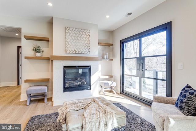 living room featuring recessed lighting, visible vents, a healthy amount of sunlight, and a glass covered fireplace