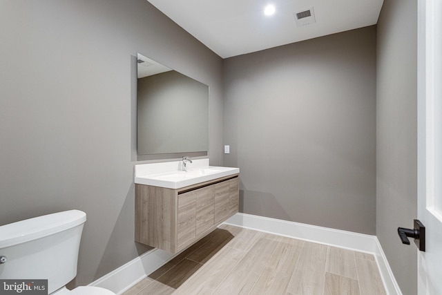 bathroom featuring visible vents, baseboards, toilet, and vanity