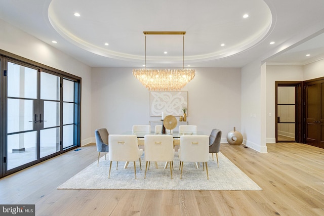 dining room featuring baseboards, light wood finished floors, an inviting chandelier, a tray ceiling, and recessed lighting