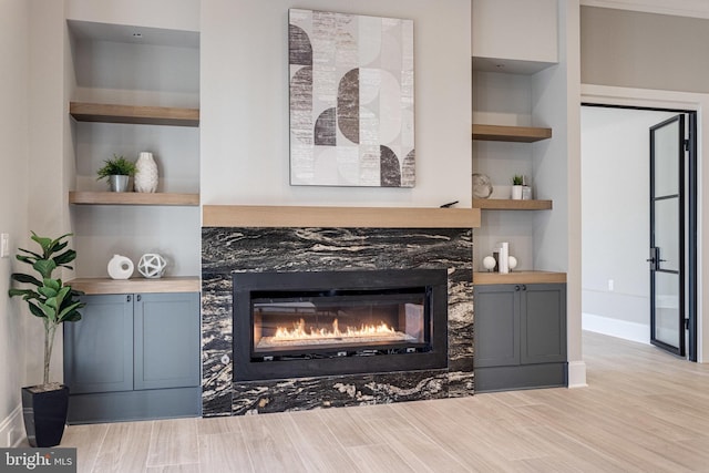 interior details featuring a premium fireplace, built in shelves, baseboards, and wood finished floors