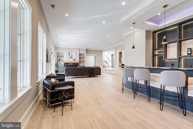 interior space with visible vents, stairway, light wood-style floors, crown molding, and baseboards