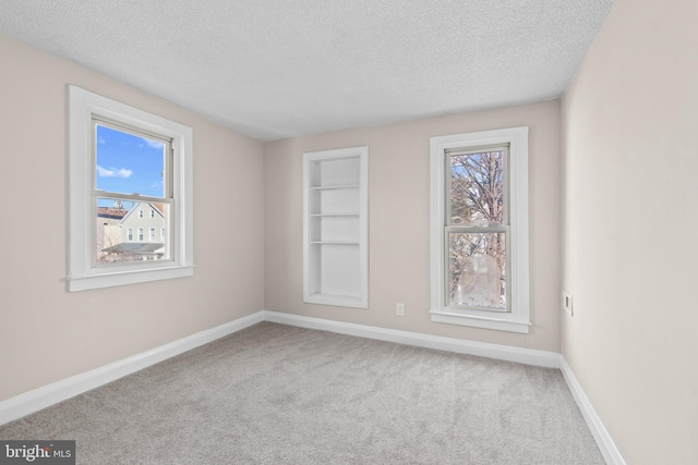 carpeted spare room with built in features and a textured ceiling