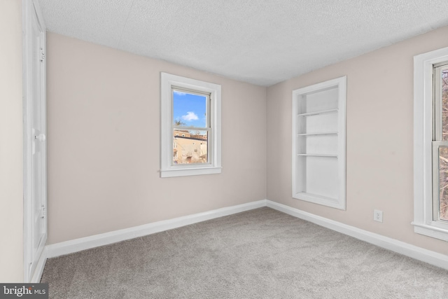 unfurnished room featuring carpet floors, built in features, and a textured ceiling