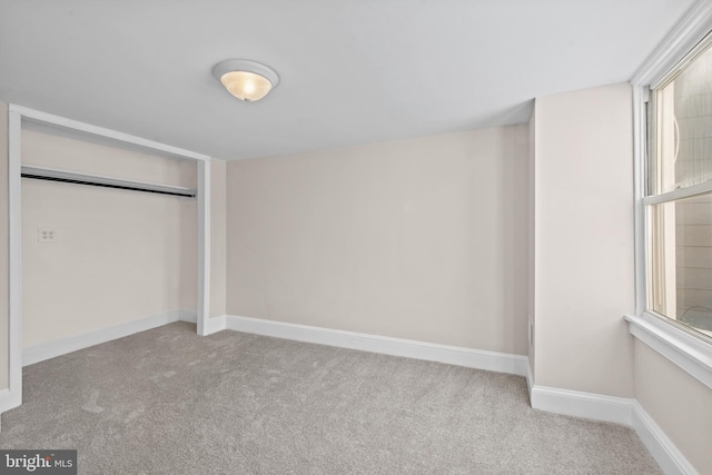 unfurnished bedroom with light colored carpet and a closet