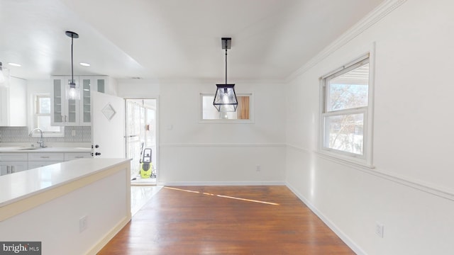 unfurnished dining area featuring sink, ornamental molding, and hardwood / wood-style floors