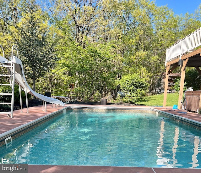 view of swimming pool featuring a wooden deck and a water slide