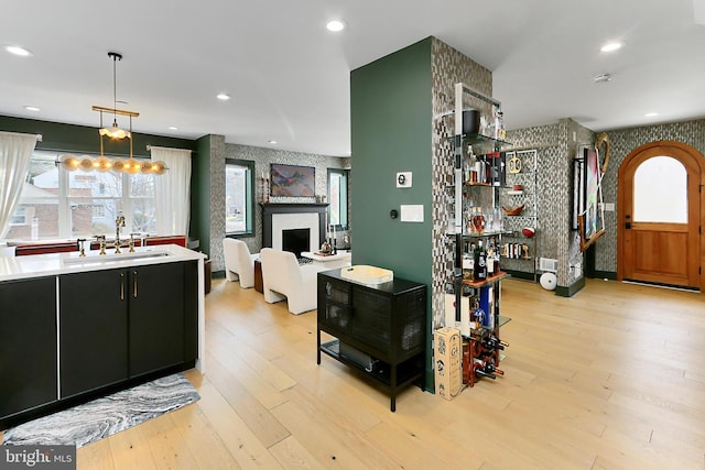 kitchen featuring sink, decorative light fixtures, and light hardwood / wood-style flooring