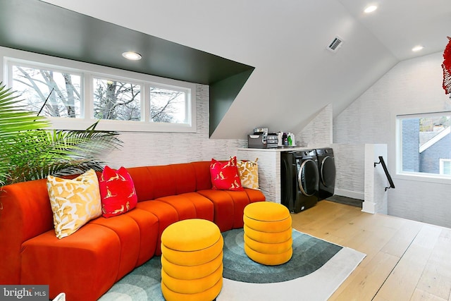 living room with vaulted ceiling, light hardwood / wood-style floors, and washing machine and dryer