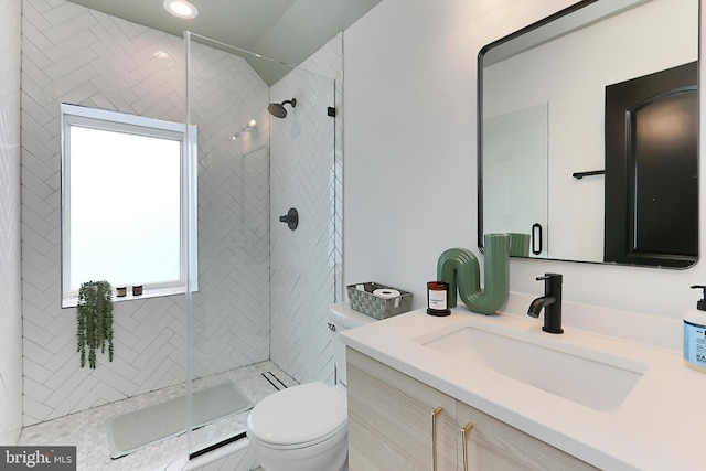 bathroom featuring vanity, tiled shower, and toilet