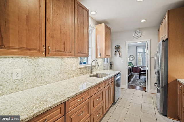 kitchen featuring light stone countertops, sink, appliances with stainless steel finishes, light tile patterned flooring, and decorative backsplash