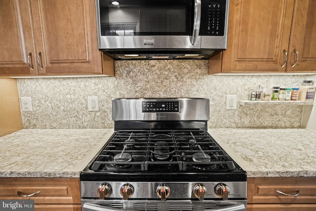 kitchen featuring appliances with stainless steel finishes, tasteful backsplash, and light stone counters