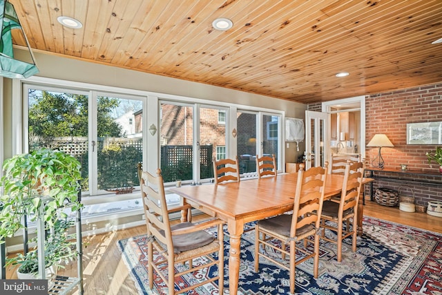 dining space featuring hardwood / wood-style floors, wood ceiling, and brick wall