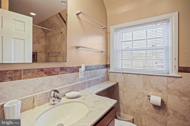 bathroom with vanity, toilet, and tile walls