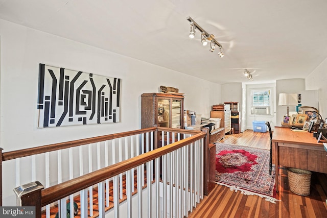 corridor with cooling unit, hardwood / wood-style flooring, and track lighting