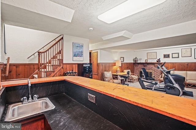 interior space featuring sink, wooden walls, a textured ceiling, and butcher block countertops