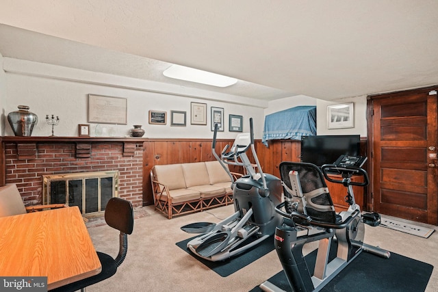 exercise area with light colored carpet, a fireplace, and wood walls