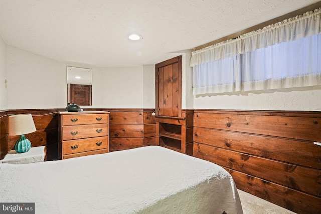 bedroom featuring a textured ceiling and wood walls