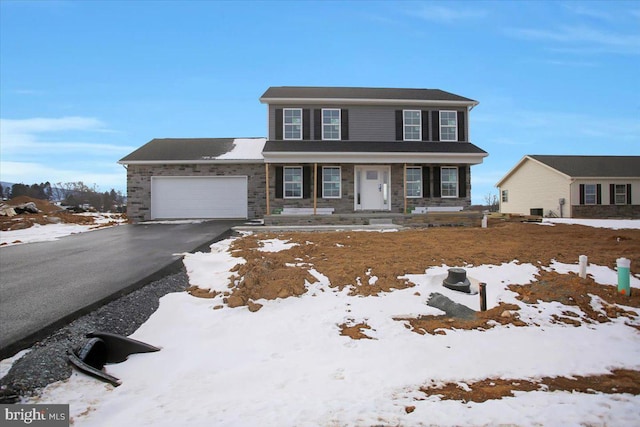 view of front facade with covered porch, driveway, stone siding, and an attached garage