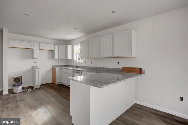 kitchen featuring sink, white cabinetry, kitchen peninsula, hardwood / wood-style flooring, and light stone countertops