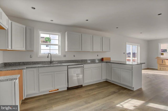 kitchen with sink, dishwasher, kitchen peninsula, light hardwood / wood-style floors, and white cabinets