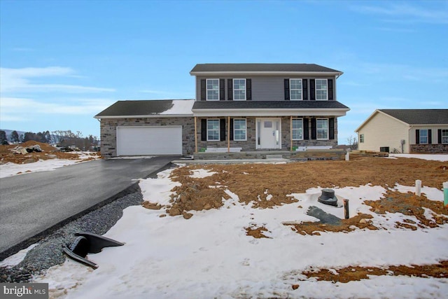 view of front of home with aphalt driveway, stone siding, covered porch, and a garage