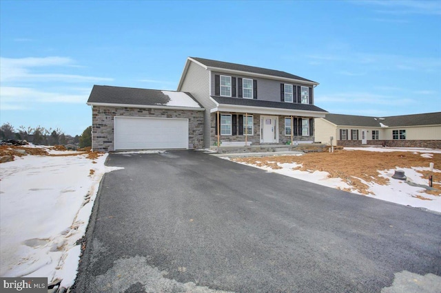 view of front of house with a garage, stone siding, driveway, and a porch