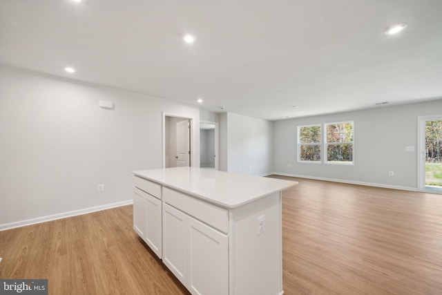 kitchen with white cabinets, a center island, and light hardwood / wood-style flooring