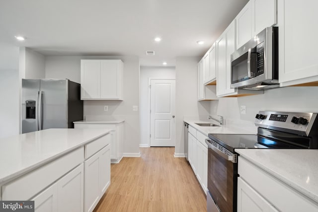 kitchen featuring stainless steel appliances, light hardwood / wood-style flooring, white cabinets, and sink