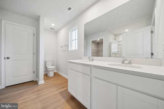 bathroom with toilet, a shower with door, wood-type flooring, and vanity