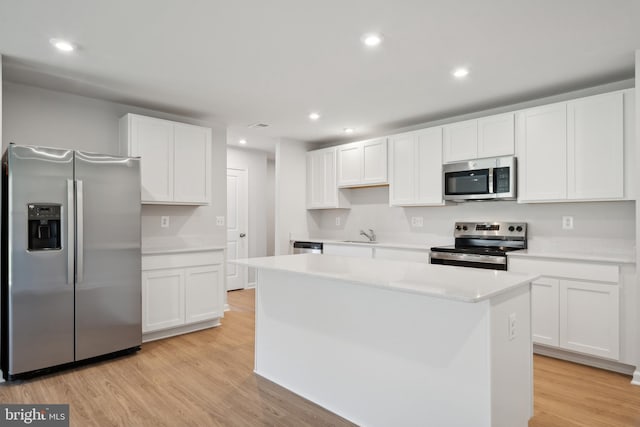 kitchen featuring a kitchen island, sink, white cabinetry, light wood-type flooring, and appliances with stainless steel finishes