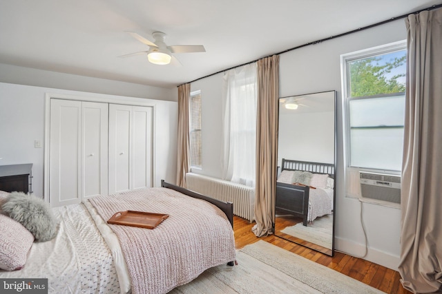 bedroom featuring hardwood / wood-style floors, ceiling fan, cooling unit, a closet, and radiator heating unit