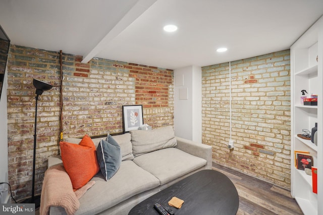 living room featuring wood-type flooring, brick wall, and beamed ceiling