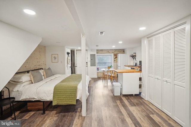 bedroom featuring dark hardwood / wood-style floors, a closet, white fridge, and electric panel