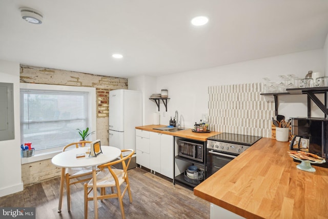 kitchen featuring white cabinets, stainless steel range with electric cooktop, black microwave, sink, and butcher block countertops