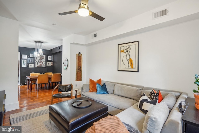 living room featuring ceiling fan with notable chandelier and wood-type flooring