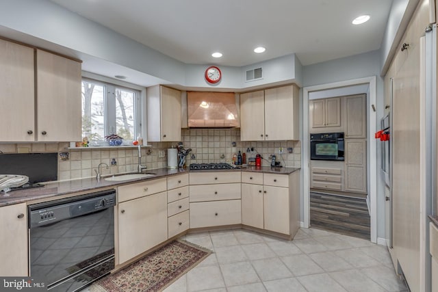 kitchen with black appliances, light brown cabinets, tasteful backsplash, sink, and custom range hood