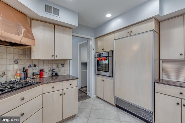 kitchen featuring premium range hood, paneled fridge, black gas stovetop, stainless steel oven, and decorative backsplash